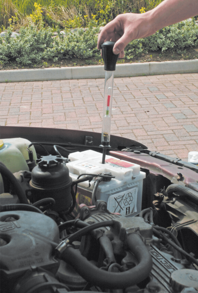 Using a Kennedy KEN5031120K hydrometer dipstick to check car engine oil levels outdoors.