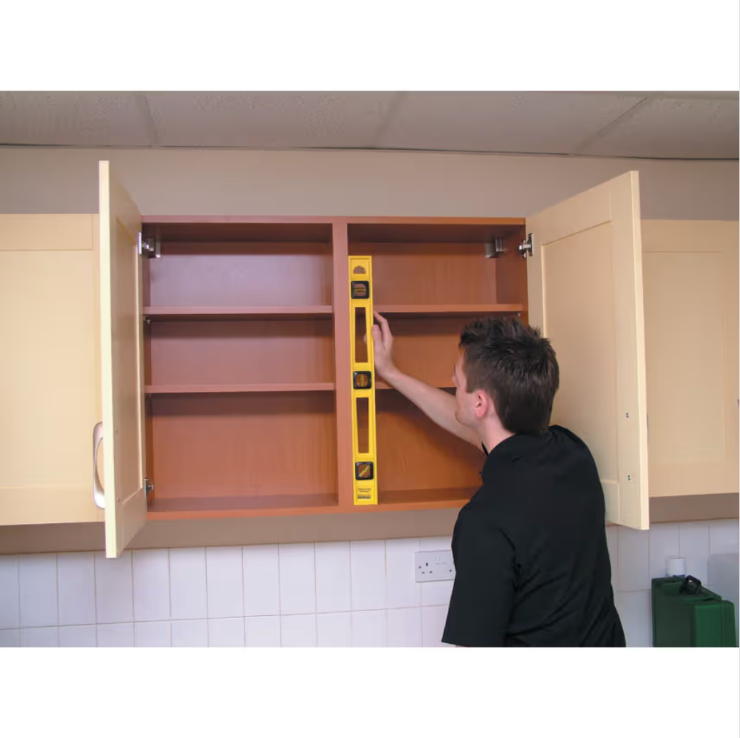 Person using a level tool on an open cabinet in a kitchen setting
