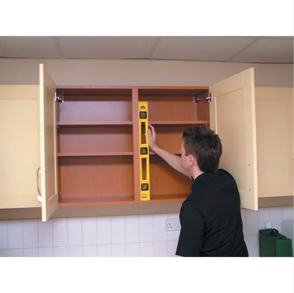 Person using a level tool on an open cabinet in a kitchen setting