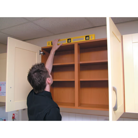 Person installing a cabinet with a level on a white wall.